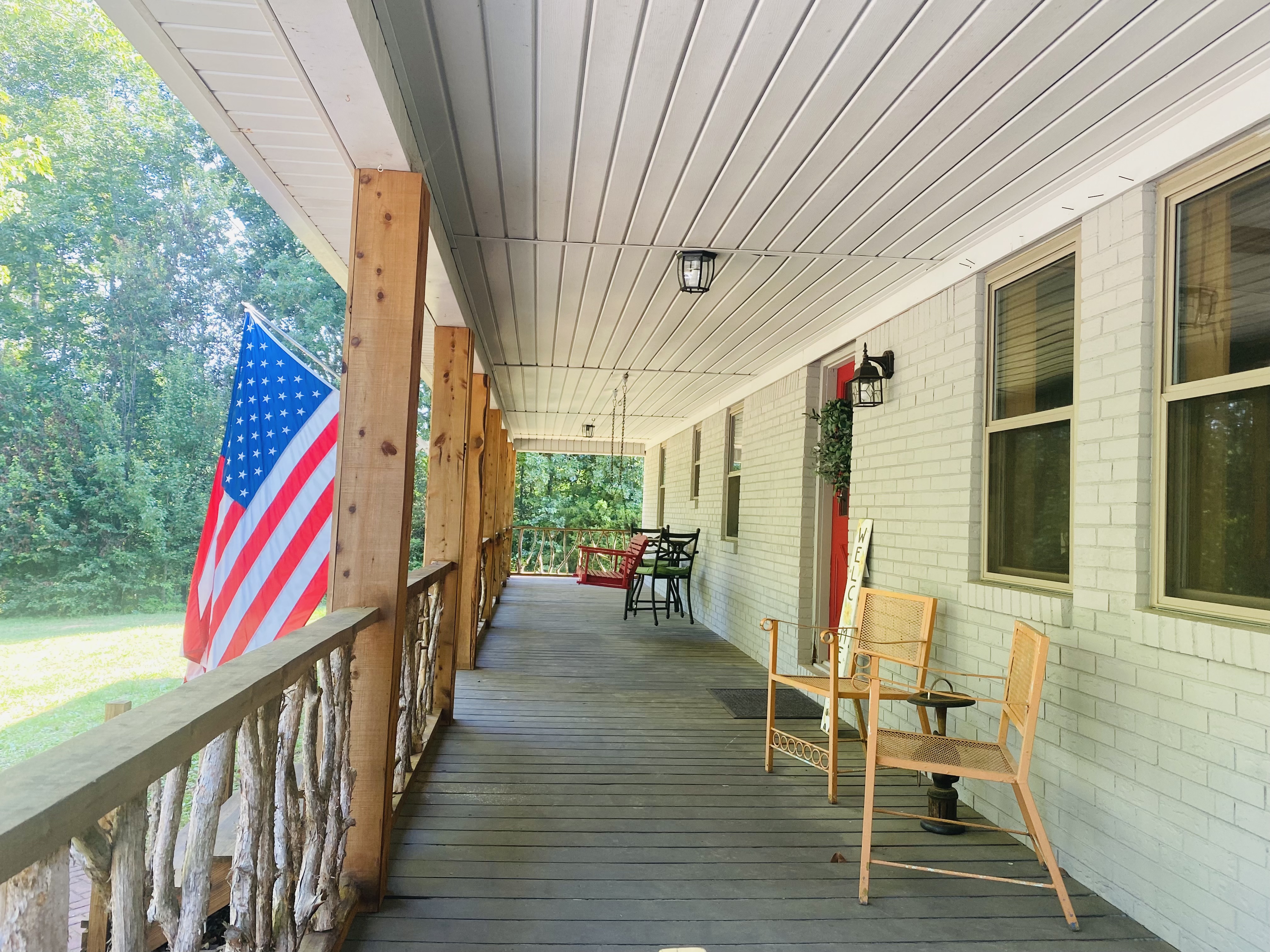 Farm home porch with handcrafted wood railing and flag