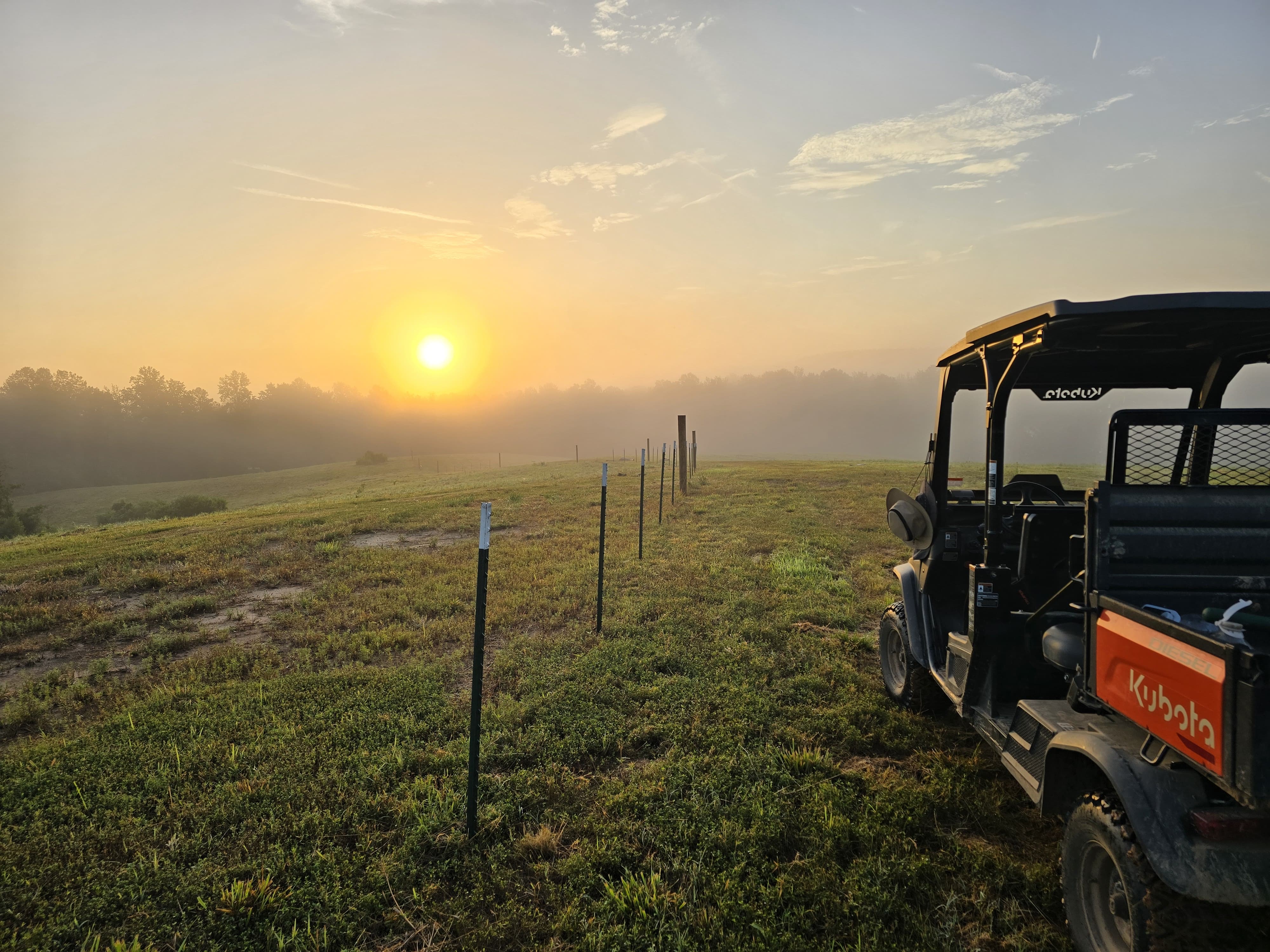 a 2x2 at sunset showing farm fields, trees, and sky.